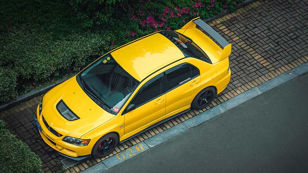 Assurance auto tous risques : une voiture sportive jaune, stationnée dans une allée verdoyante.