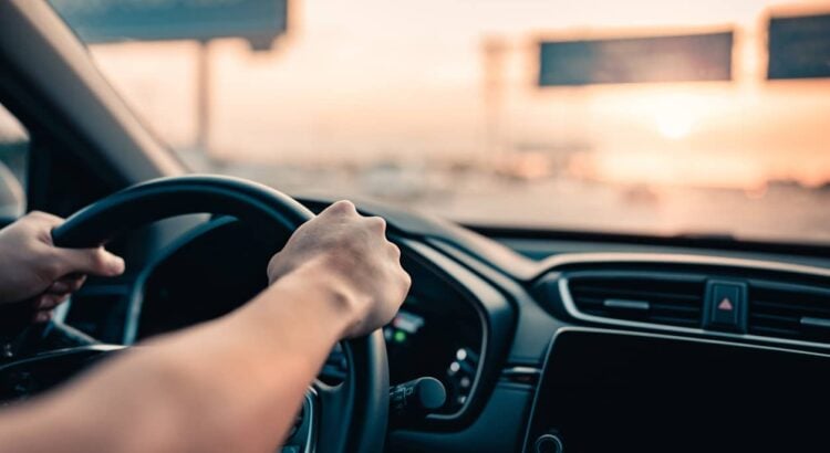 Hand of man driving car on the road.